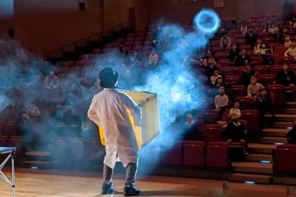 ステージから客席に向かって巨大段ボール空気砲の放つキビートの後ろ姿