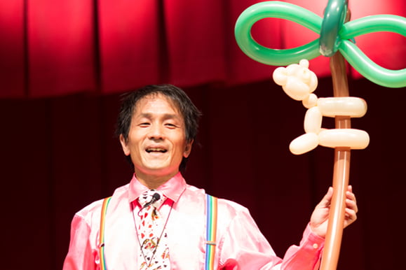 木に登る猿の風船パフォーマンスを披露するキビート